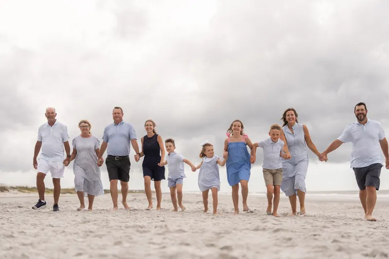 Ten people stand shoulder-to-shoulder across the sand under gray skies at Vilano Beach, St. Augustine.