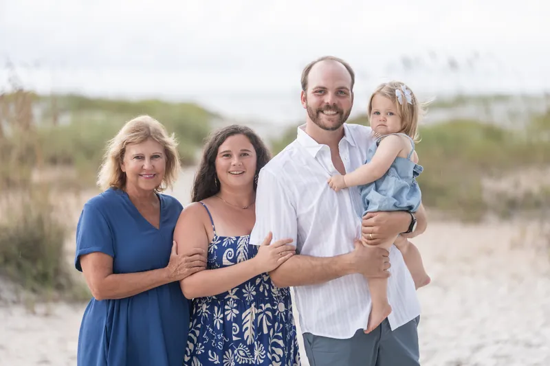 Four adults and a toddler stand close together on the beach at Vilano Beach on an overcast day.
