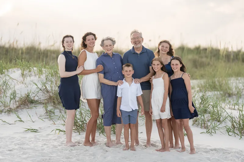 Casual family gathering of ten adults and children stands on the beach at St. Augustine Beach at sunset.