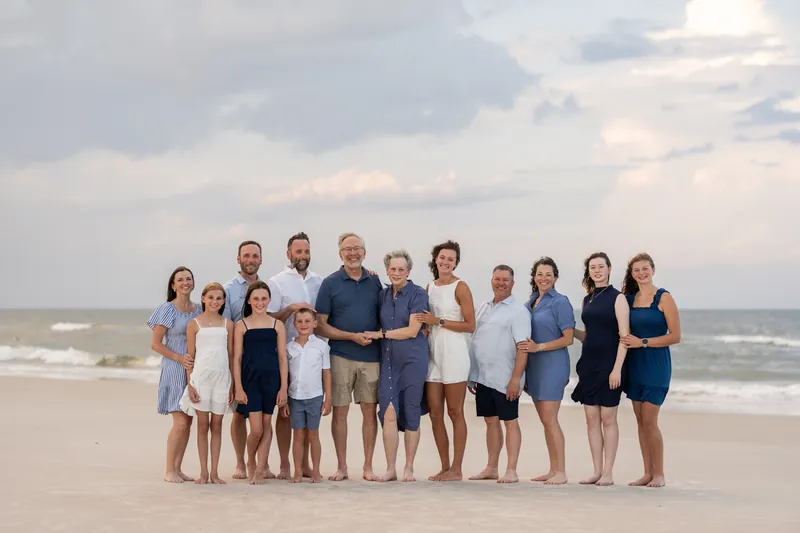 Kimberly's extended family stands shoulder-to-shoulder facing the camera on the beach, dressed in coordinated blues
