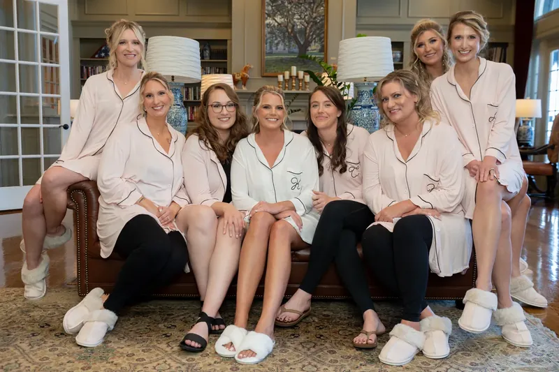 Kimberly and seven female friends sit together in matching cream button-ups and black pants on a stone floor at River House