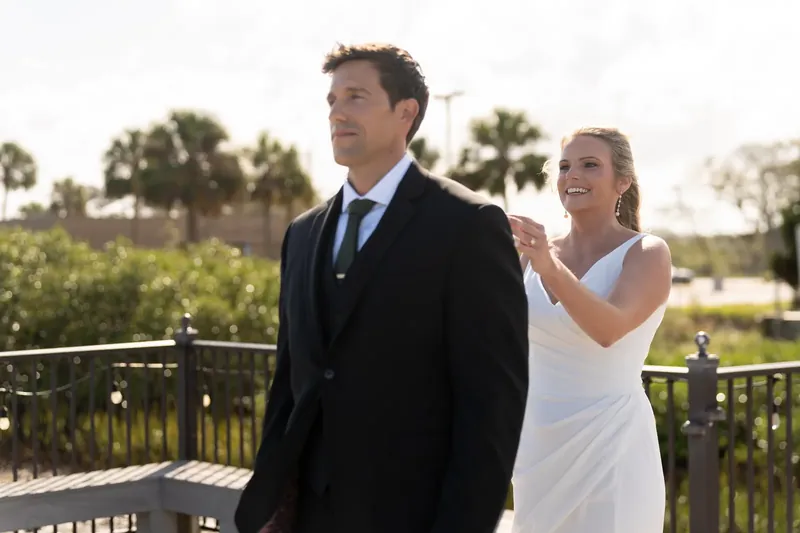 Landon and Kimberly stand together on a deck overlooking green grounds at River House Events.