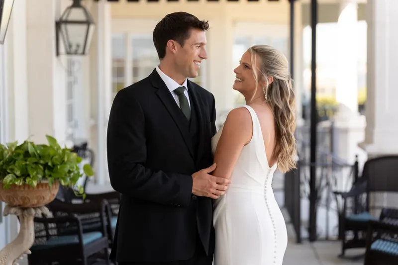 Landon and Kimberly smile at each other while strolling arm in arm along the outdoor covered space.