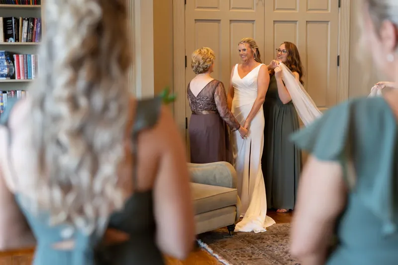 Kimberly stands center in white as bridesmaids surround her, checking final details before the ceremony at River House
