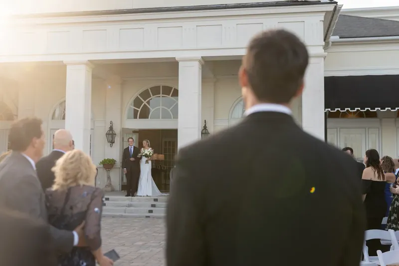 Landon stands on the front steps of River House Events as guests watch the ceremony from the courtyard below.