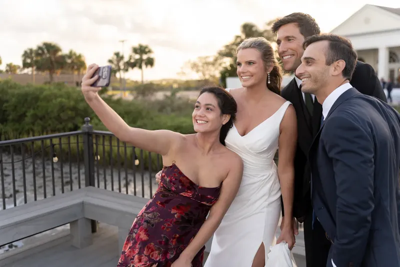 Four wedding guests take a selfie on a deck overlooking the water at River House Events, St. Augustine.