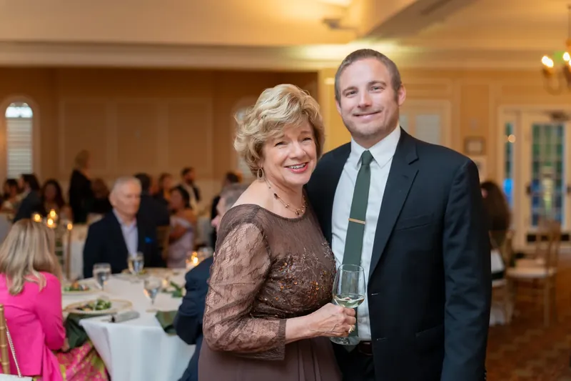 Landon poses with a woman in a brown lace dress during the reception celebration at River House Events.