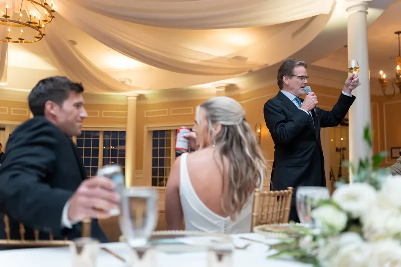 A groomsman delivers a toast while Kimberly and Landon sit at the head table during the reception.