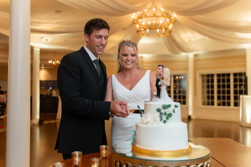 Landon and Kimberly cut into their white wedding cake at River House Events, St. Augustine.