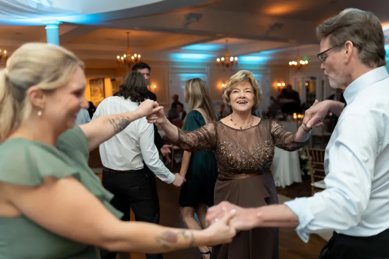 Guests dance together during the reception as blue uplighting illuminates the ballroom.