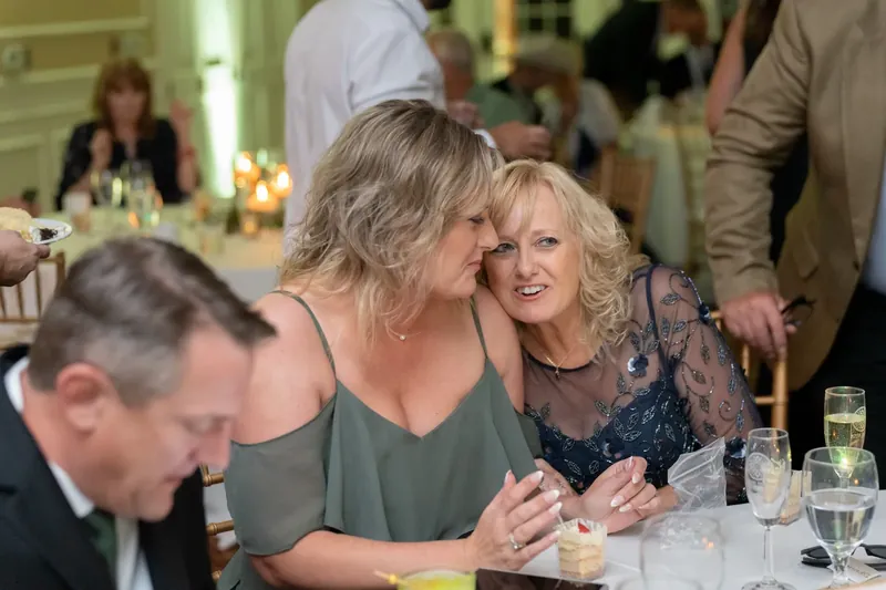 Guests laugh together at a dining table during the reception at River House Events.