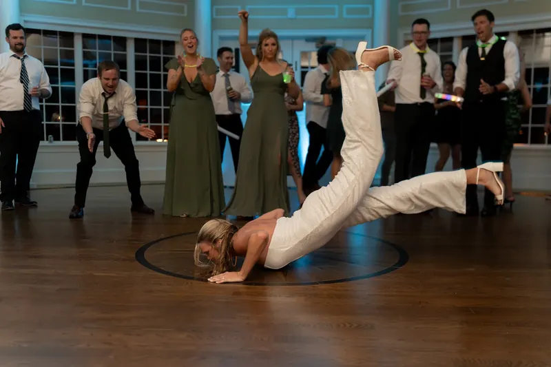 A guest performs a dramatic backbend on the dance floor while others watch and cheer.