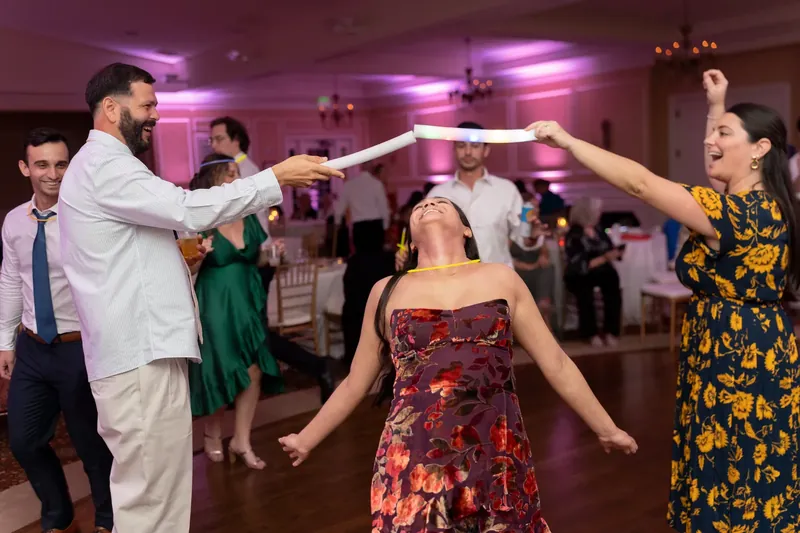 Four guests form a bridge with their arms as a woman dances underneath during the party.