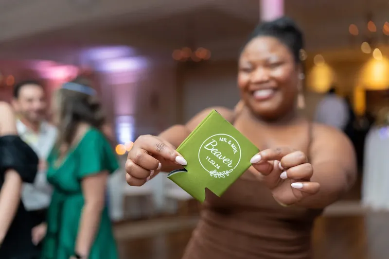 A woman holds up a green drink koozie at River House Events during the reception.