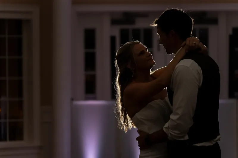 Kimberly and Landon embrace in soft purple lighting during an indoor moment at their reception.
