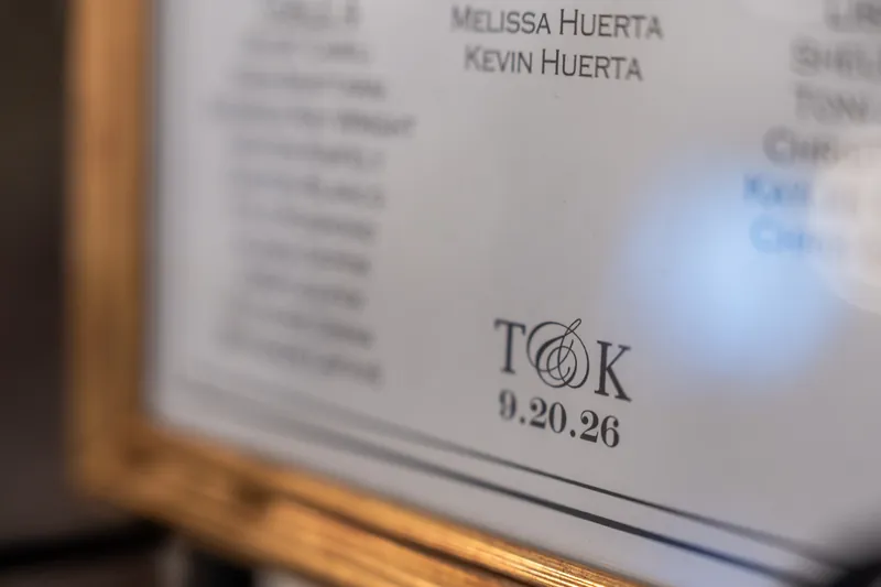 Close-up of an ornate wedding program showing names and the date 09.20.26 at The Treasury on the Plaza.
