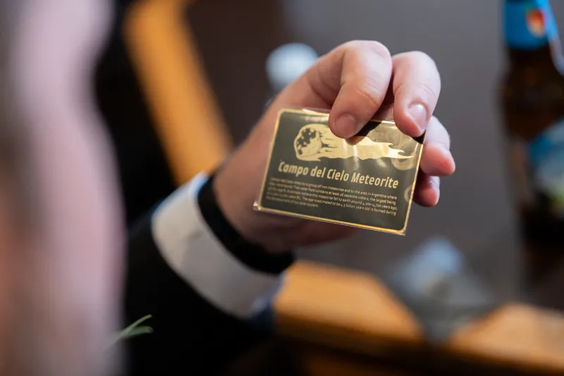 A hand displays a gold wedding medallion engraved with the couple's names at The Treasury on the Plaza.
