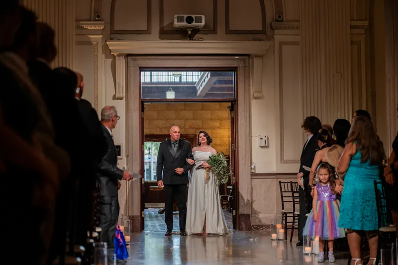 A couple exchanges vows beneath The Treasury's grand arched doorway as family and young attendants gather nearby.