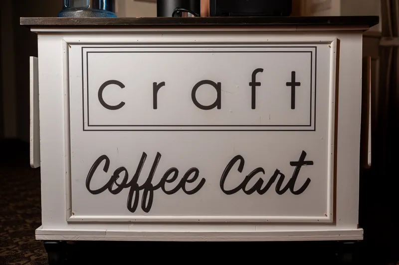 A white craft coffee cart sign sits ready for reception guests at The Treasury on the Plaza.