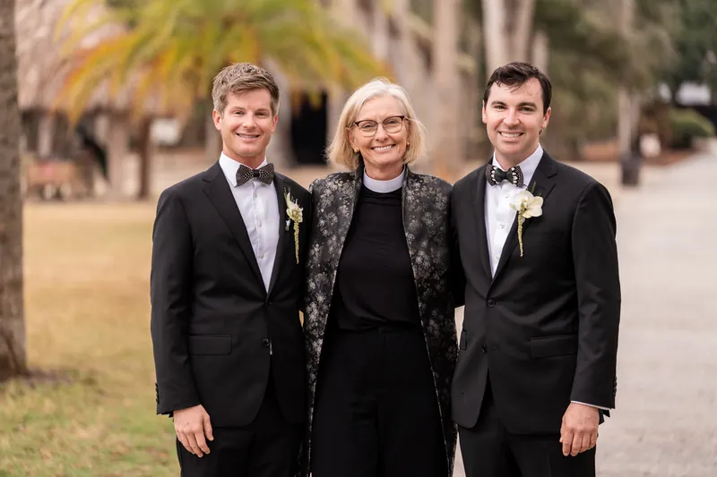 Austin and Kirkland with their officiant under palm trees