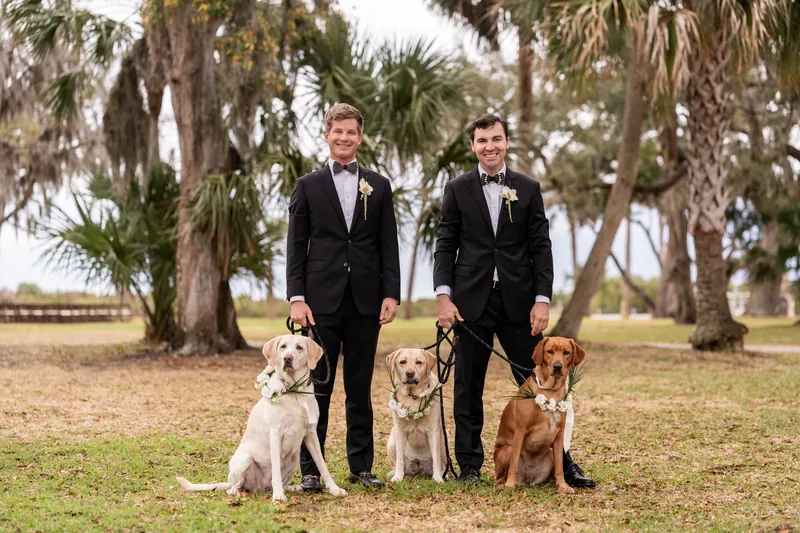 Austin and Kirkland with their three dogs wearing floral garlands on the grounds