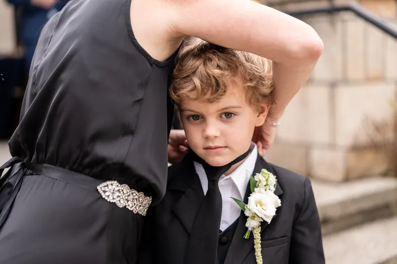Ring bearer with curly hair and boutonniere before the ceremony
