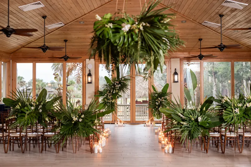 Ceremony space with gold circular arch decorated with tropical greenery and candles