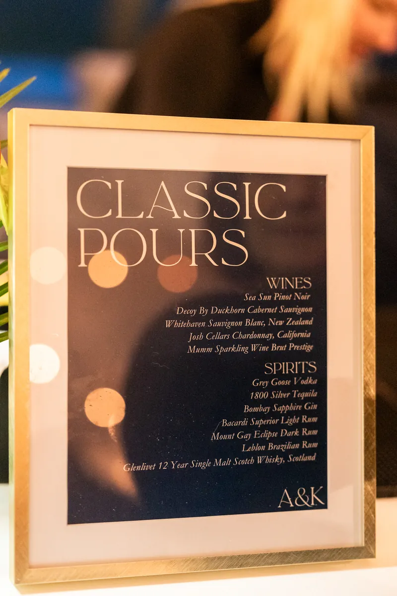 Classic Pours bar menu sign with A&K monogram and bokeh lights