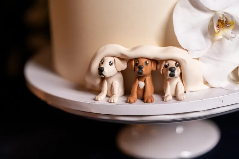 Close-up of three fondant dog figurines of Layla, Leah, and Lana hidden under the wedding cake