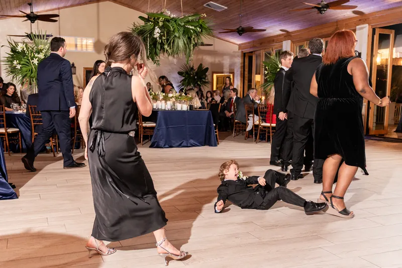 Ring bearer sliding across the dance floor surrounded by guests