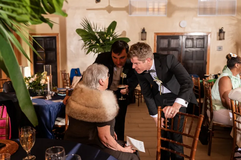 Austin and Kirkland chatting with a guest at their table during the reception