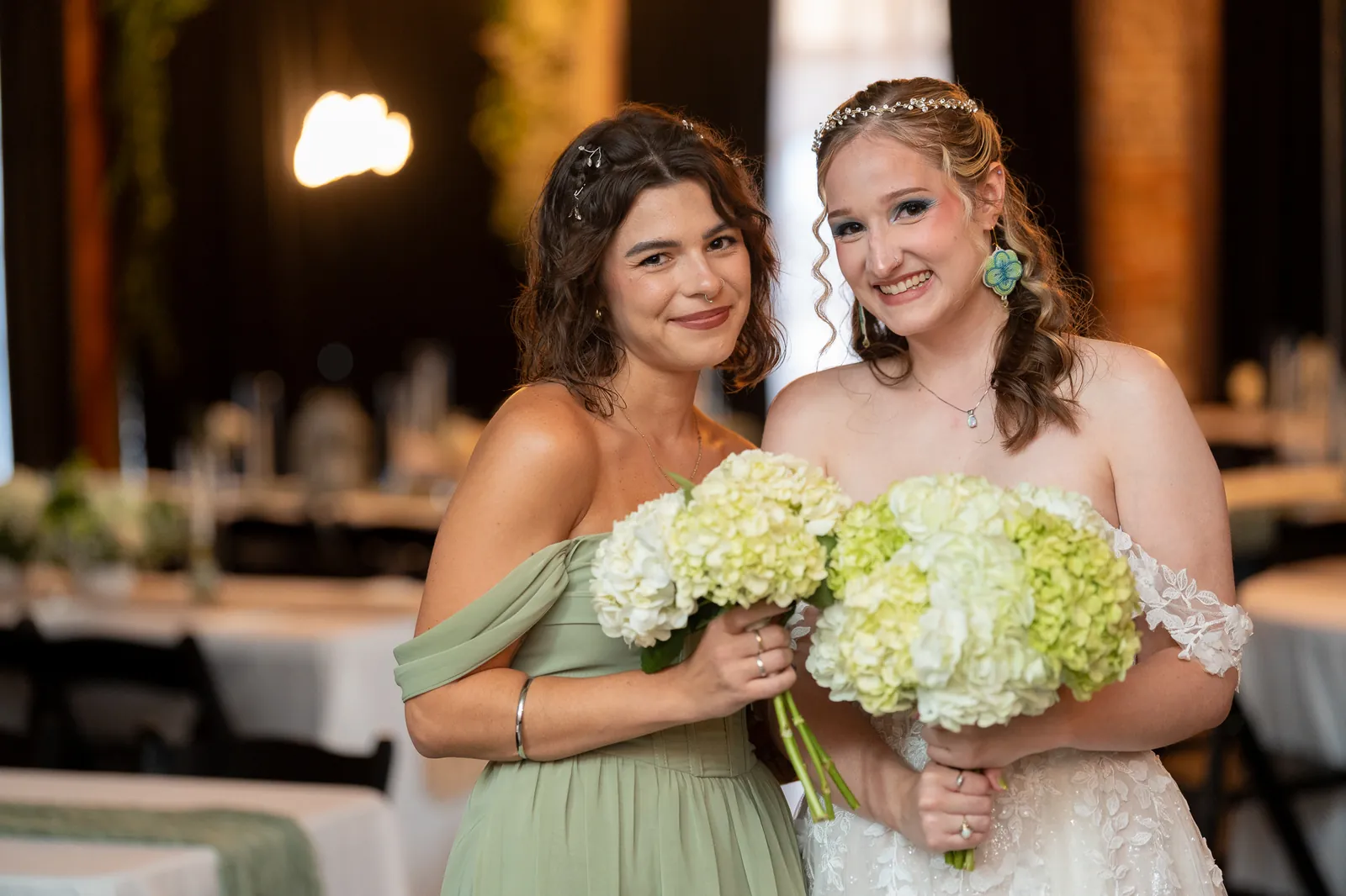 Bride Kyra with bridesmaid holding hydrangea bouquets in sage green dress