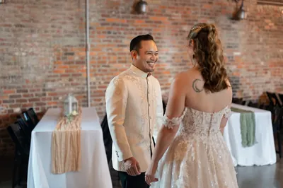 First look groom Judd smiling in Barong Tagalog with brick wall at Brick and Beam