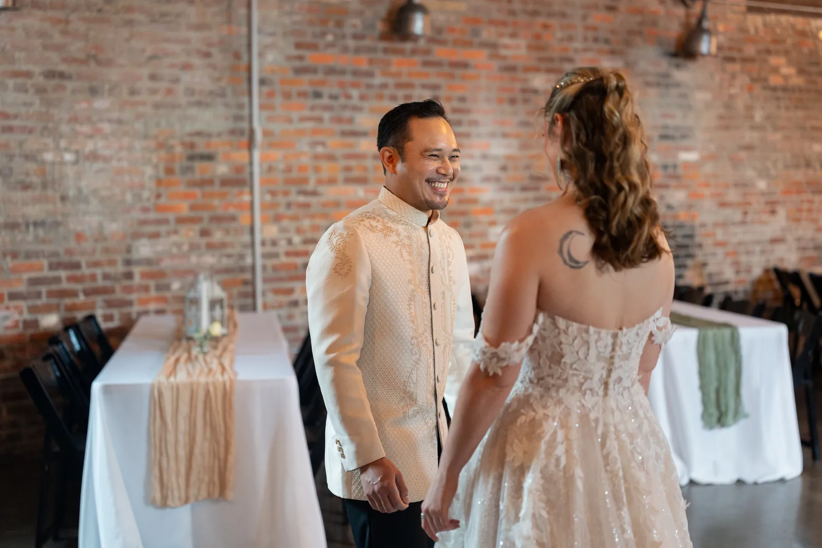 Groom reaction during first look with exposed brick wall at Brick and Beam
