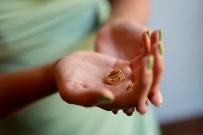 Child's hand displaying golden wedding rings in palm outdoors