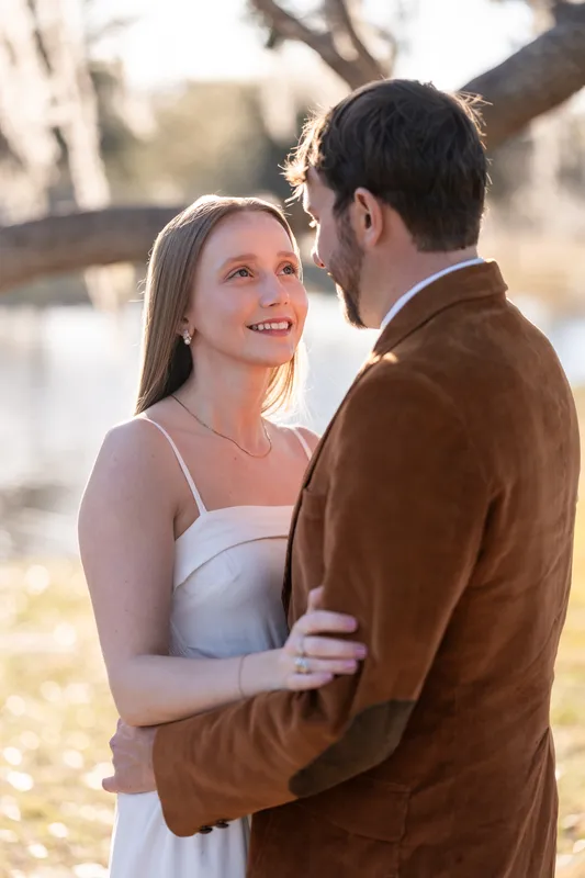 Close-up of Lacey looking up at Josh with golden backlight and the pond behind them