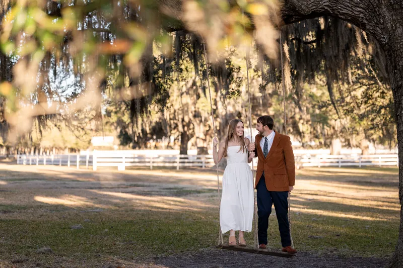 Lacey and Josh standing together by the rope swing under a large oak