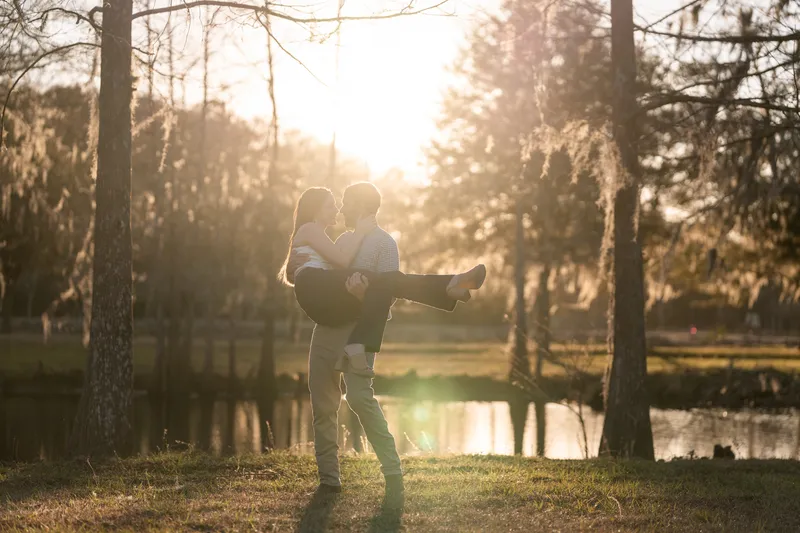 Josh lifting Lacey with the sun setting behind them over the pond