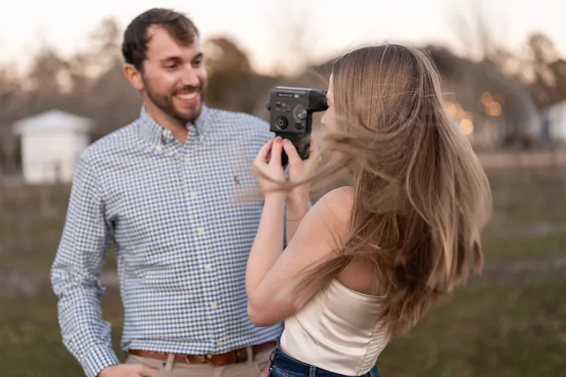Lacey filming Josh with a vintage Super 8 camera, her hair blowing in the wind