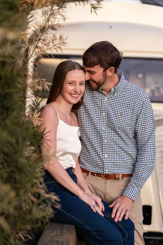 Close-up of Lacey smiling while Josh nuzzles her near a vintage truck