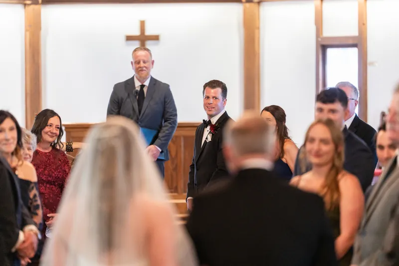 Kevin and Lauren stand at the altar facing each other as wedding guests look on from the pews.
