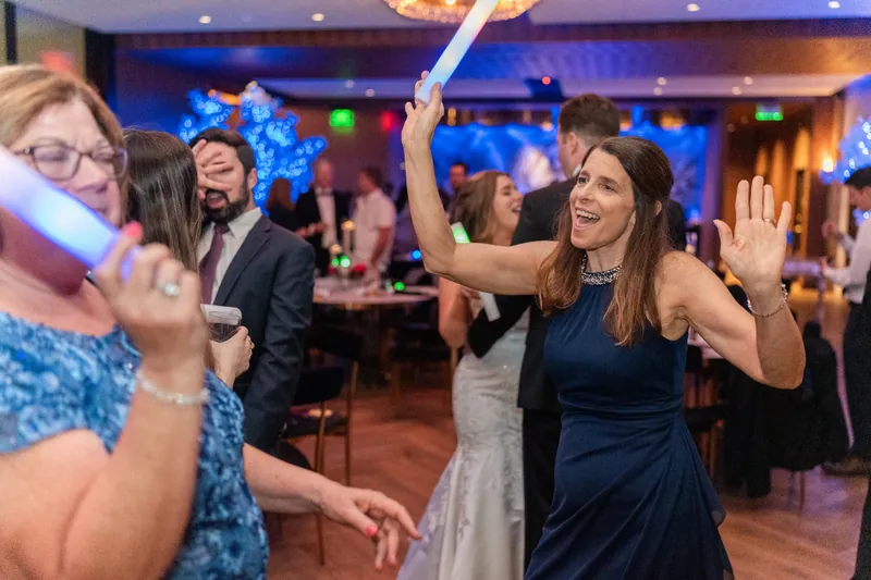 Wedding guests dancing and celebrating on the dance floor under blue lighting