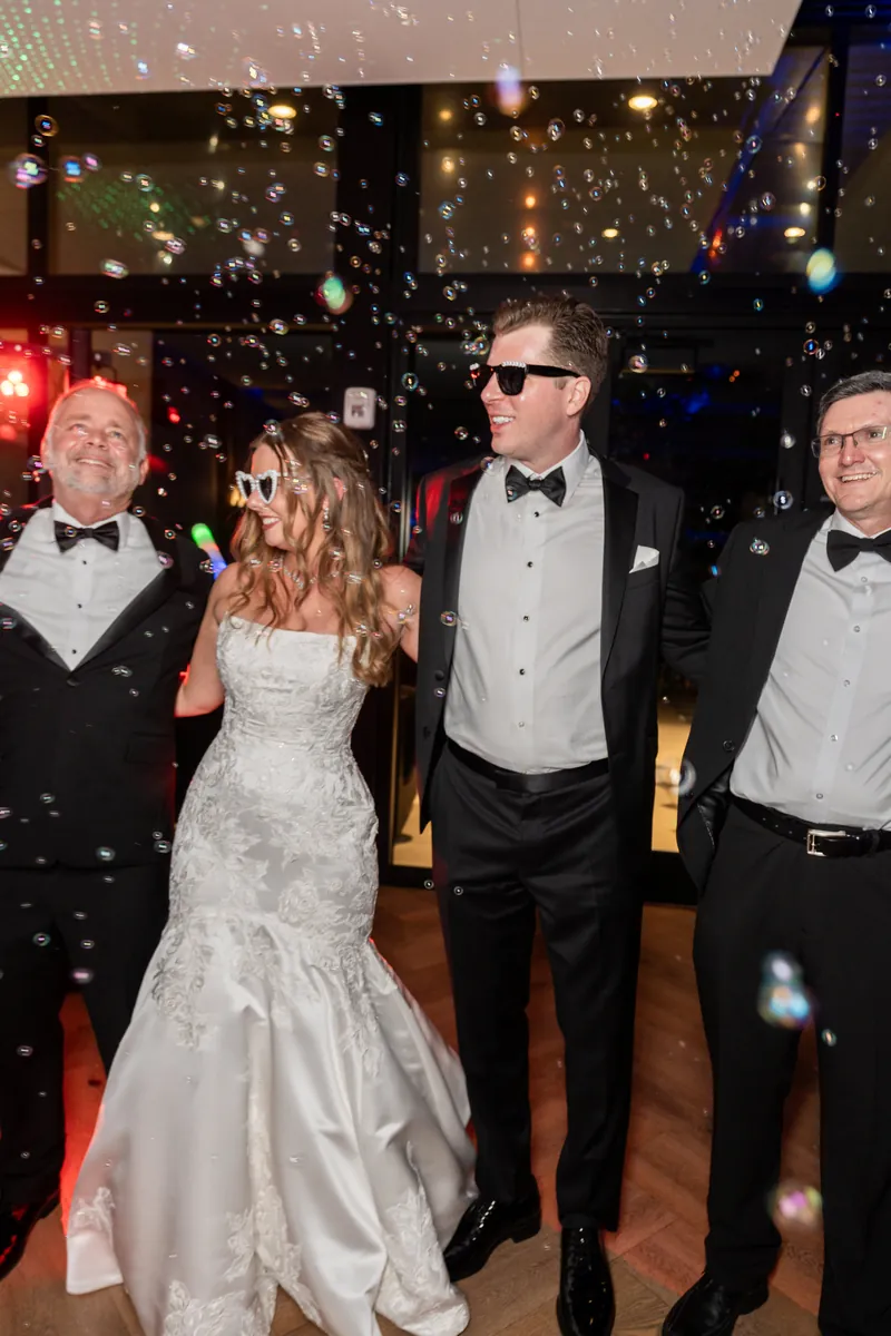 Lauren and Kevin dance on the reception floor while confetti falls around them and guests in formal attire watch nearby.