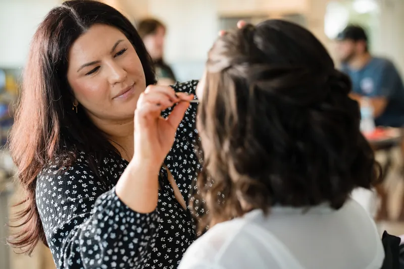 A woman in a polka-dot top fastens an earring on Laurel before the ceremony.