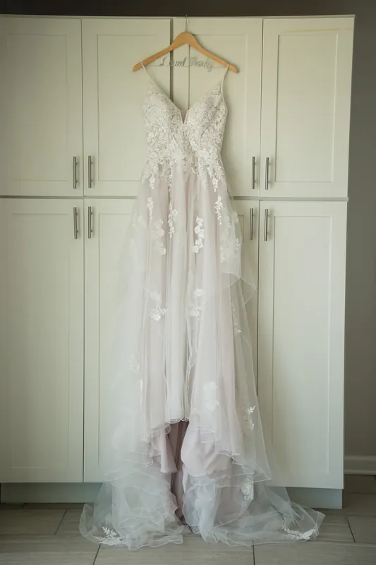Laurel's beaded white gown hangs on display against white cabinetry at The White Room, St. Augustine.