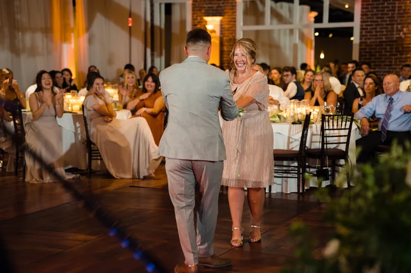 A guest dances with a woman in a beige dress on the wooden floor at The White Room reception.