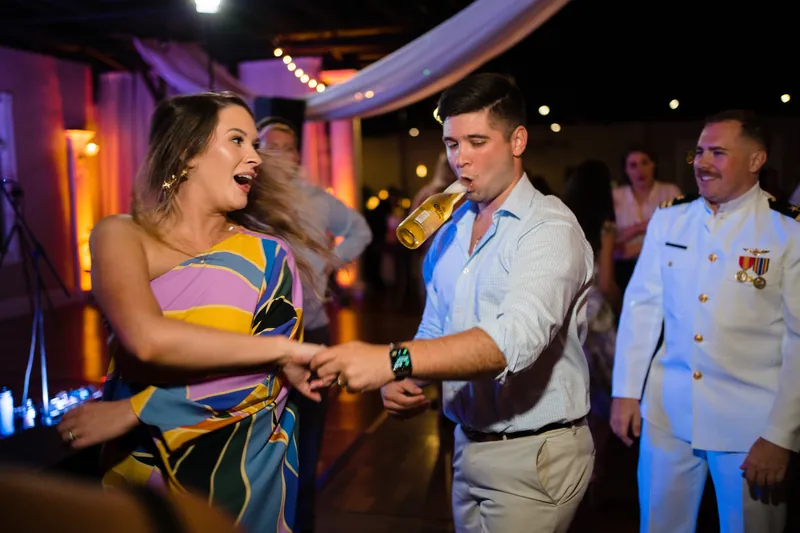Laurel dances with a guest in a colorful striped dress while uniformed officers watch and smile nearby.