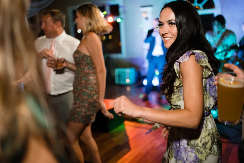 Laurel smiles brightly while dancing with friends in a patterned dress.