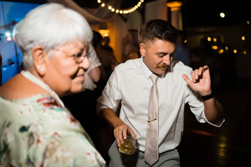 Jake speaks animatedly with a guest holding a drink at The White Room reception.