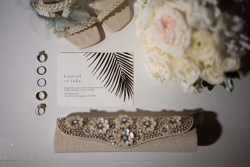 Laurel and Jake's wedding stationery arranged with beaded bridal belt, rings, and blush florals.